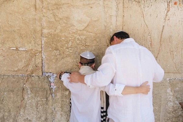 A boy and his father facing a wall during a bar mitzvah, an experience of liminality.