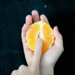 An open tangerine with somebody sticking their finger in it