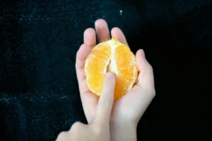 An open tangerine with somebody sticking their finger in it
