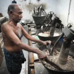 A shirtless man grinding stones