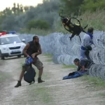 Migrants trying to navigate a security fence