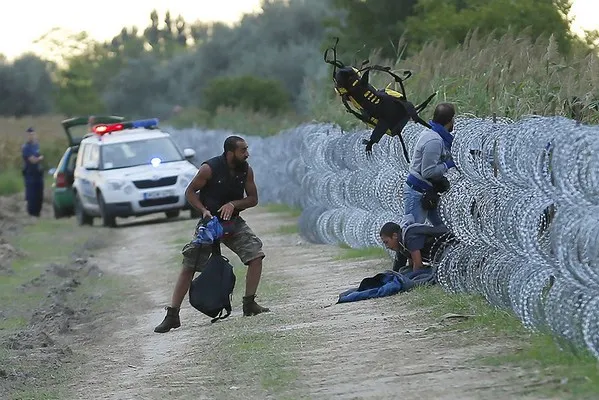 Migrants trying to navigate a security fence