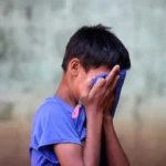 A young boy hiding his tears with his t shirt