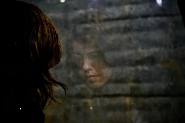A woman's reflection in a window during an identity crisis