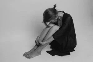 black and white shot of a woman sat on the floor with her head in her knees