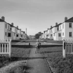 A child riding a tricycle along a path of carbon copy homes