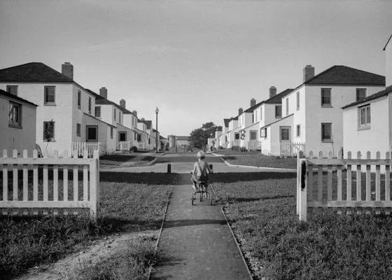 A child riding a tricycle along a path of carbon copy homes