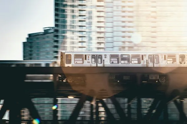 An urban vista with a train crossing a bridge in front of high rise buildings