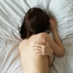A woman lying on bed hugging herself