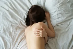 A woman lying on bed hugging herself