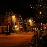 A nightime christmas scene of a street with snow and the orange glow