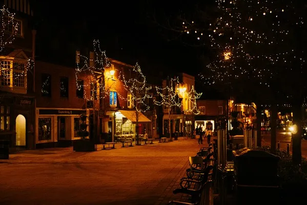 A nightime christmas scene of a street with snow and the orange glow