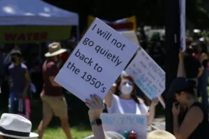 A feminist holding a placard saying 'i will not go back to the 1950's'.