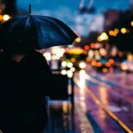 A night shot of a person carrying an umbrella