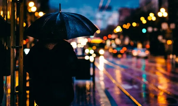A night shot of a person carrying an umbrella