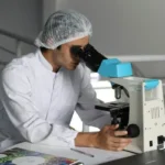 A scientist looking into a microscope.